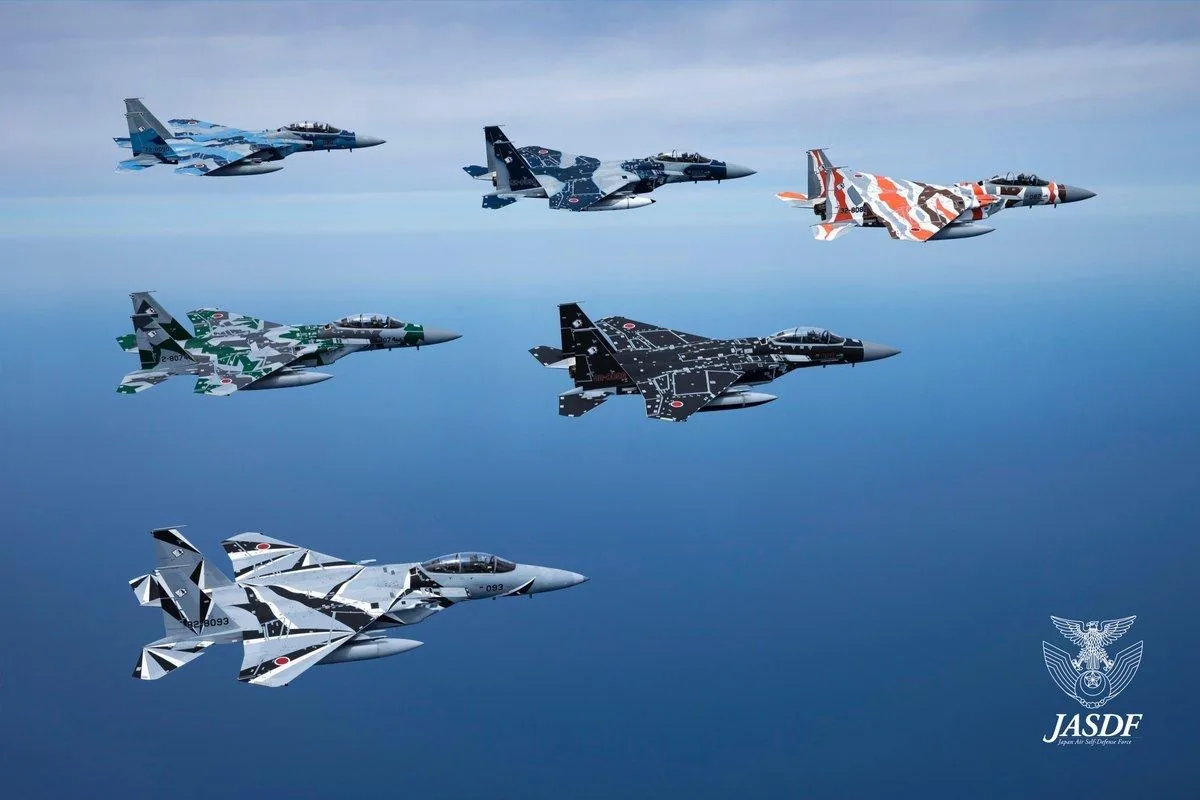 Six Japan Air Self-Defense Force F-15Js in geometric aggressor liveries, flying in formation.